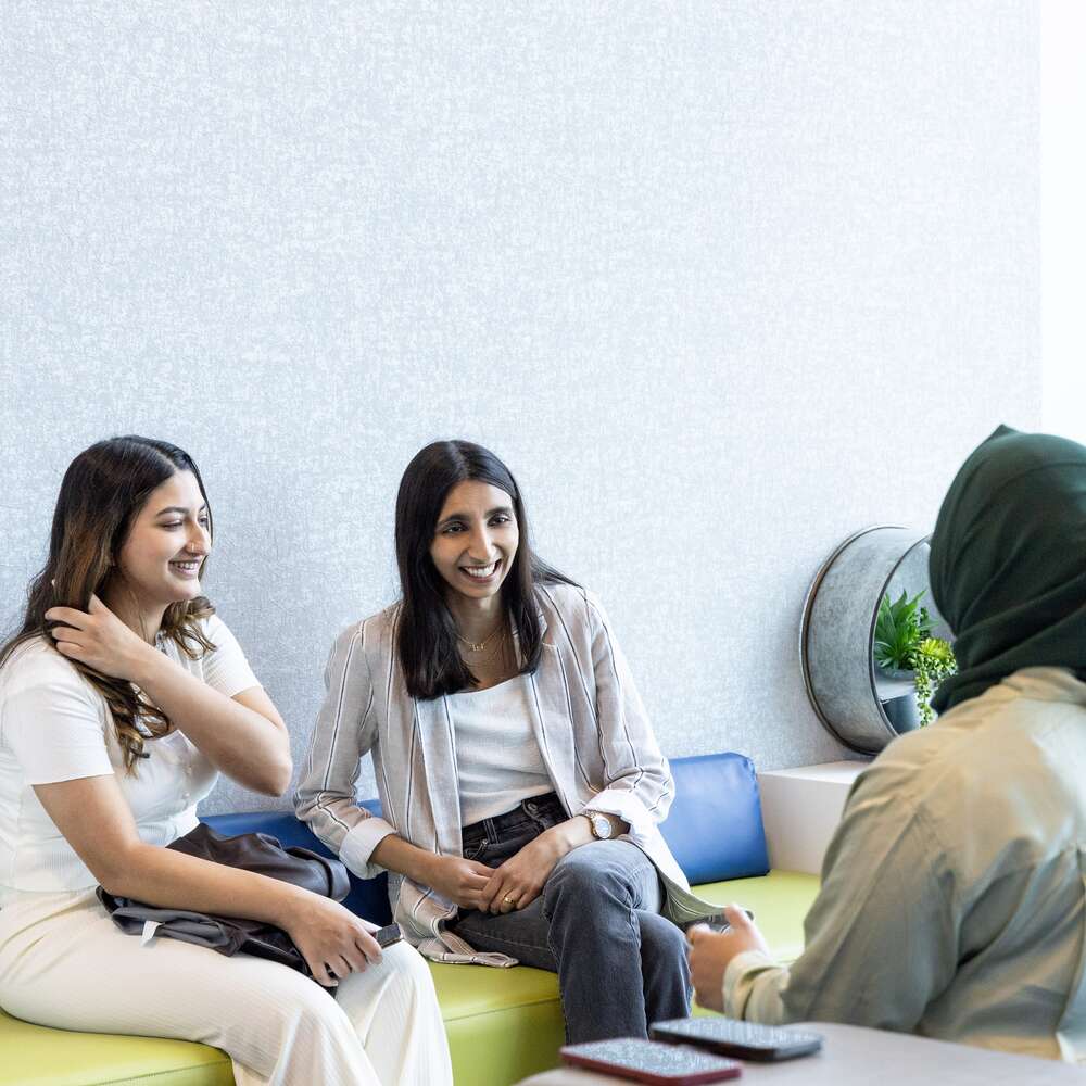 Three cheerful geotabber girls are sitting in the office and chatting