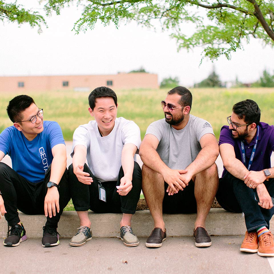 A group of Geotab employees sitting outside smiling together.