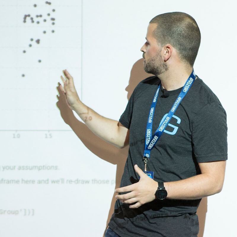 A man in grey Geotab shirt pointing at a graph on a screen