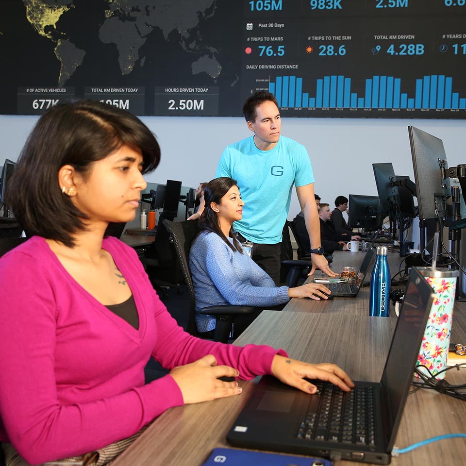 Geotab employees working together on their computers.