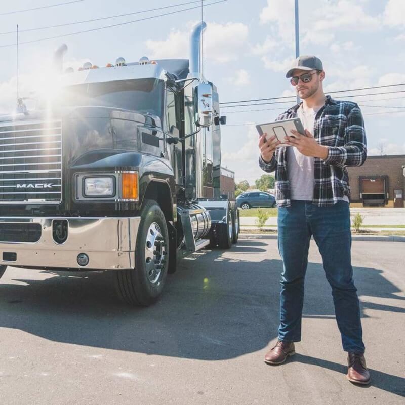 A large truck parked outside with a man wearing a hat standing beside it