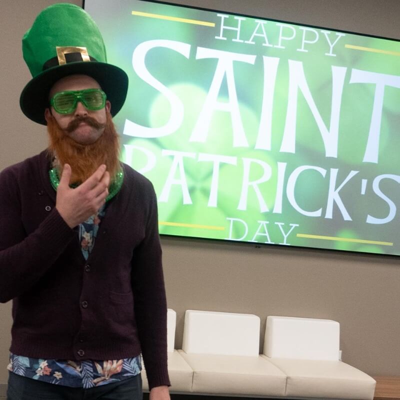 Man wearing a green st.patrick's day hat, green glasses, and a fake beard