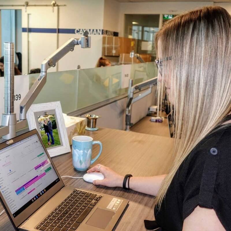 A blond woman working at a desk on a laptop computer