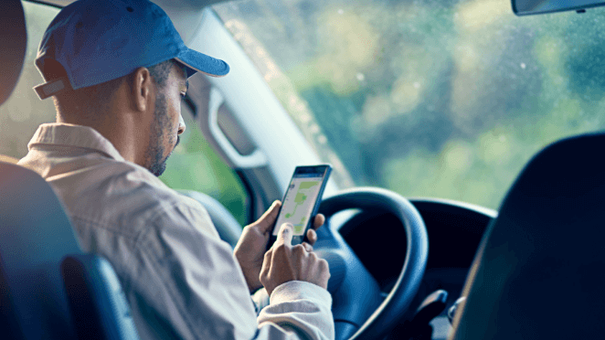 An image of a truck driver holding and interacting with the Geotab app on their smartphone.