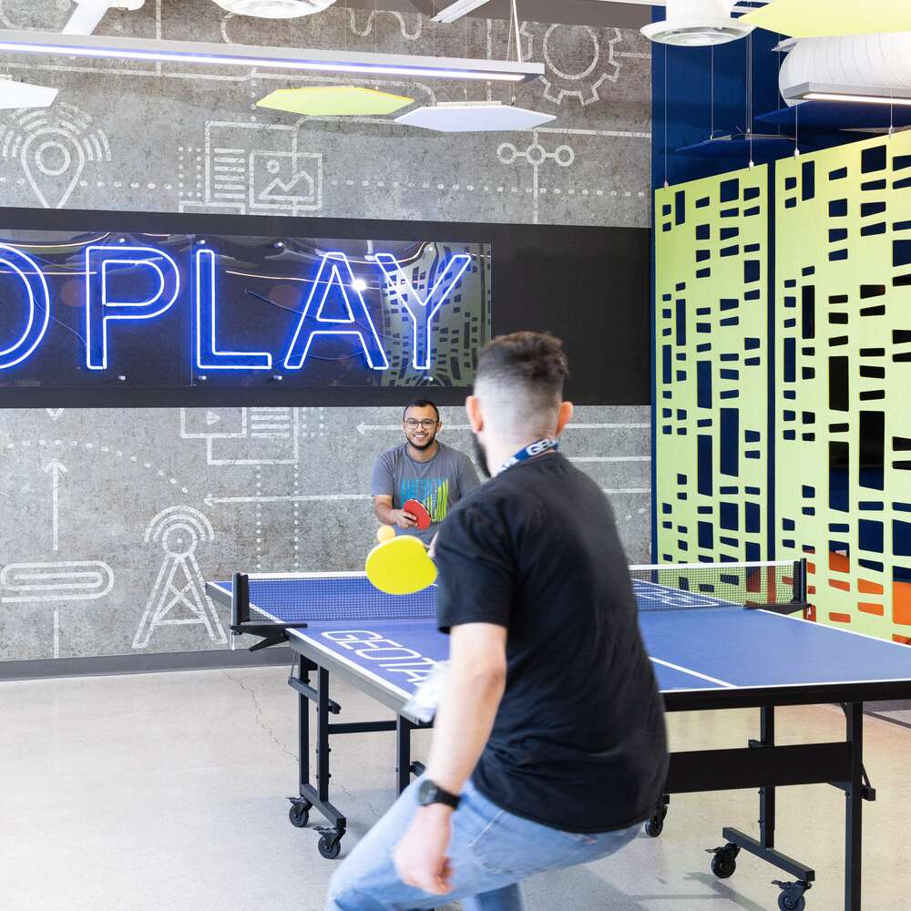 Two guys in t-shirts play ping pong in the game room