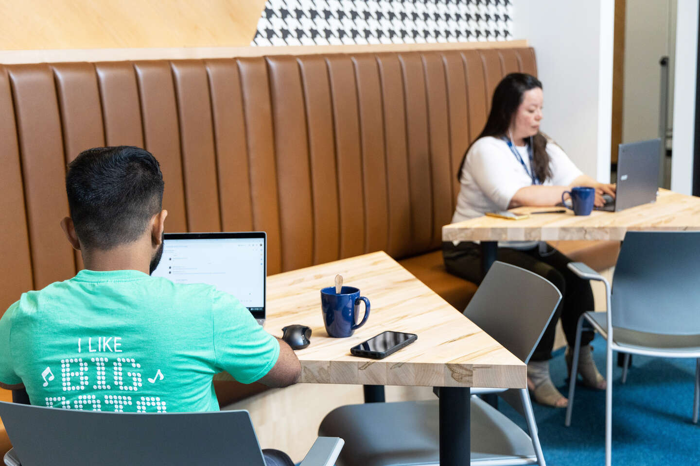 Two Geotabbers working on laptops. Guy on the left wearing green T-shirt and woman on the right wearing white.