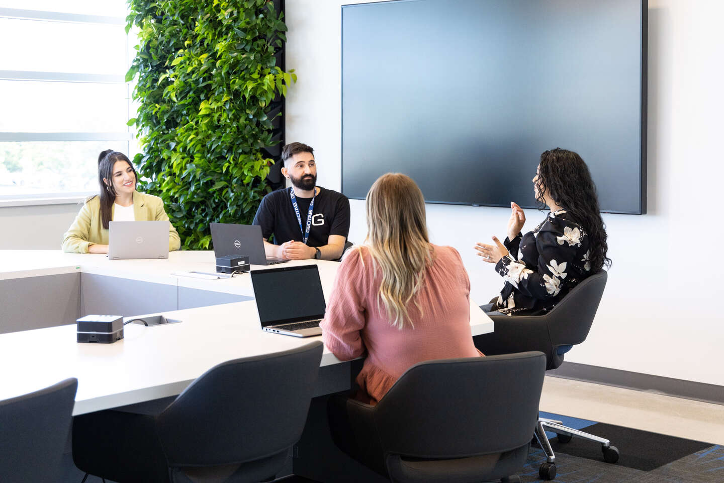 Four people are discussing something in the office. Everyone is looking at one woman who is telling something.